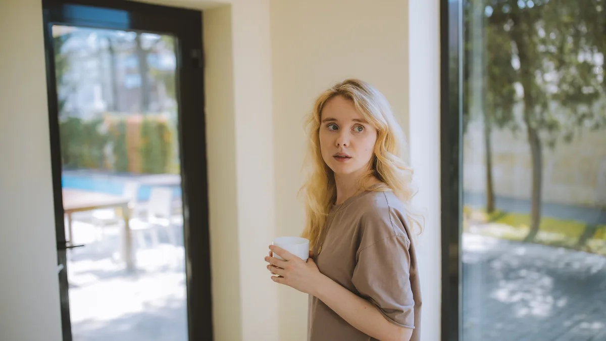 A person pausing with a coffee by a window, deciding whether automation is worth it yet