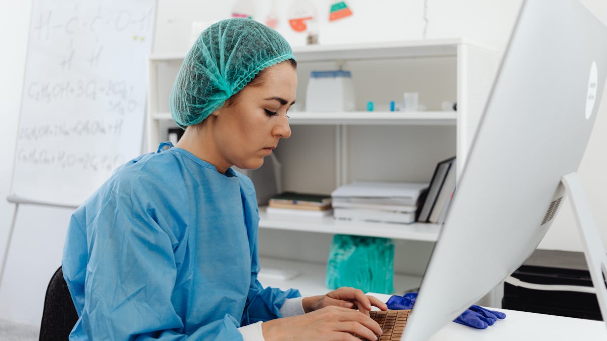 A healthcare professional entering notes at a computer workstation